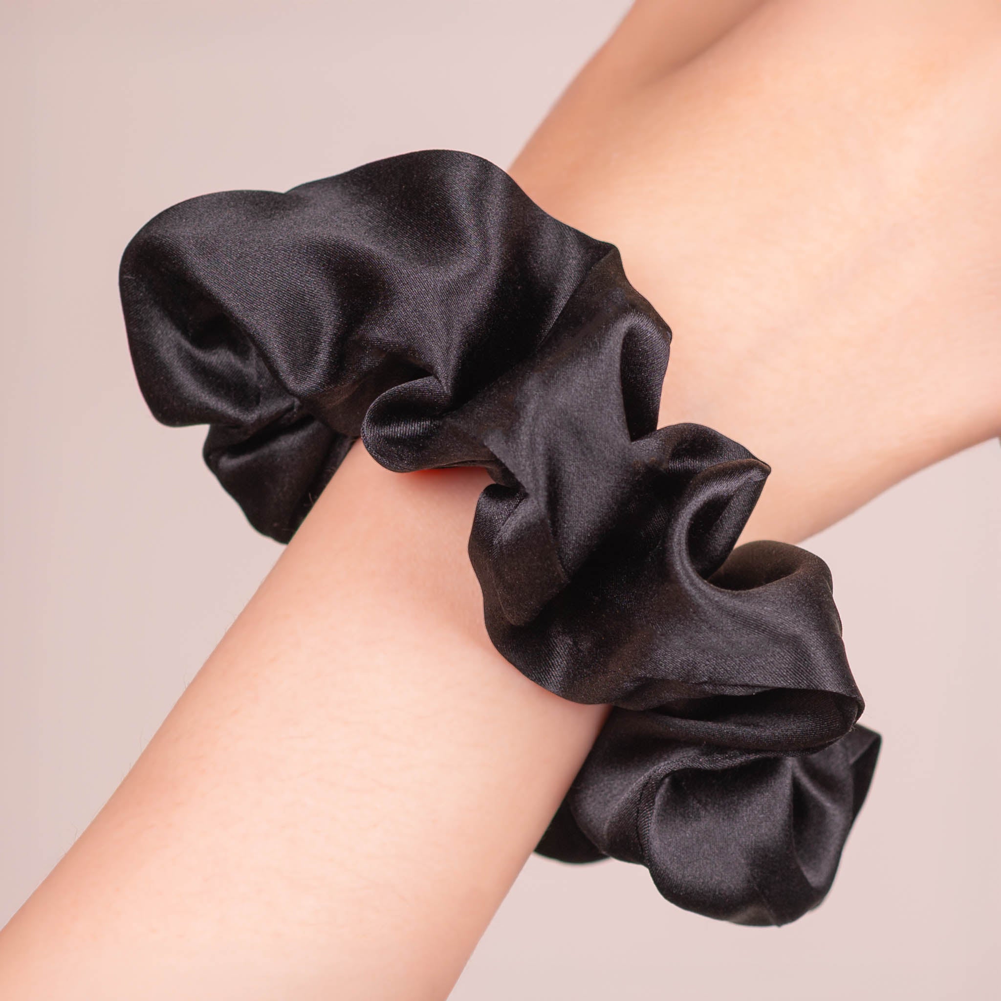 Large Silk Scrunchie in Black worn on a wrist, showing a natural soft sheen and gentle drape.