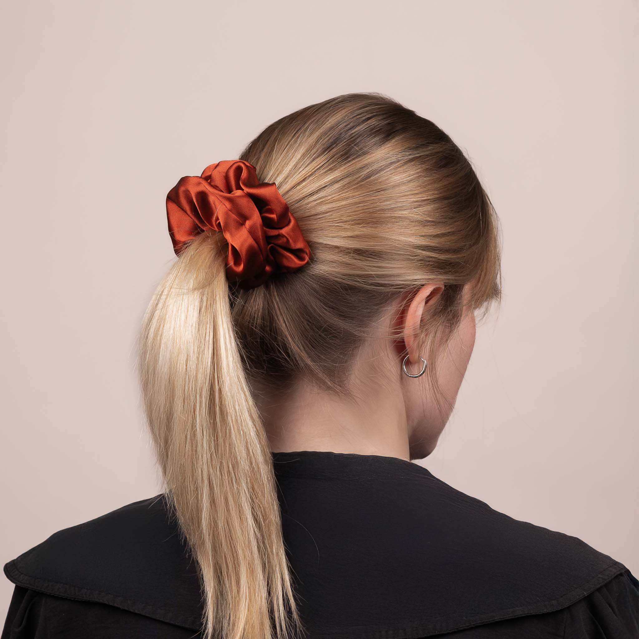 Side view of the Large Silk Scrunchie in Deep Terracotta securing hair in a low ponytail, with a soft sheen and drape.
