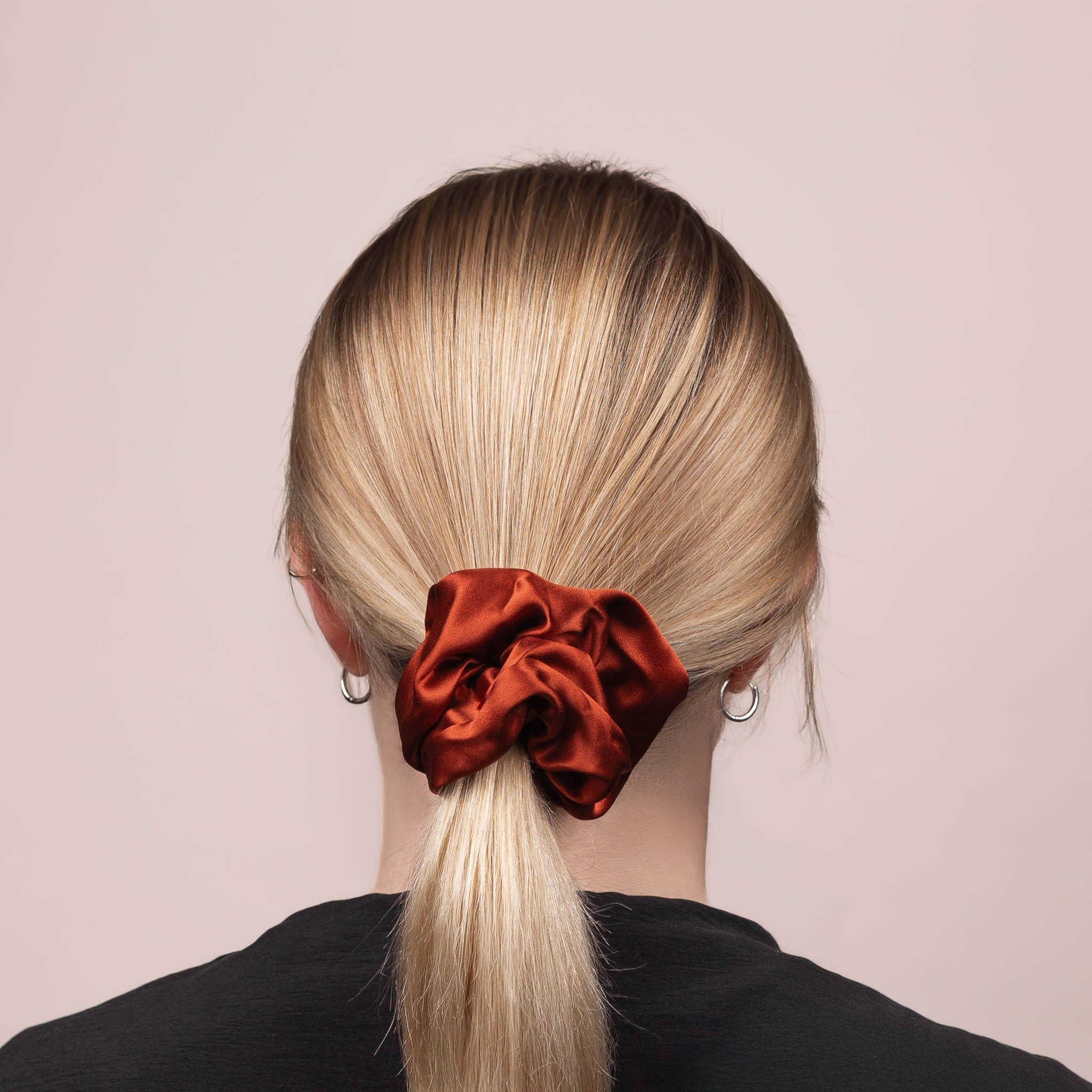 Back view of the Large Silk Scrunchie in Deep Terracotta, securing hair in a low ponytail, with a soft sheen and drape.