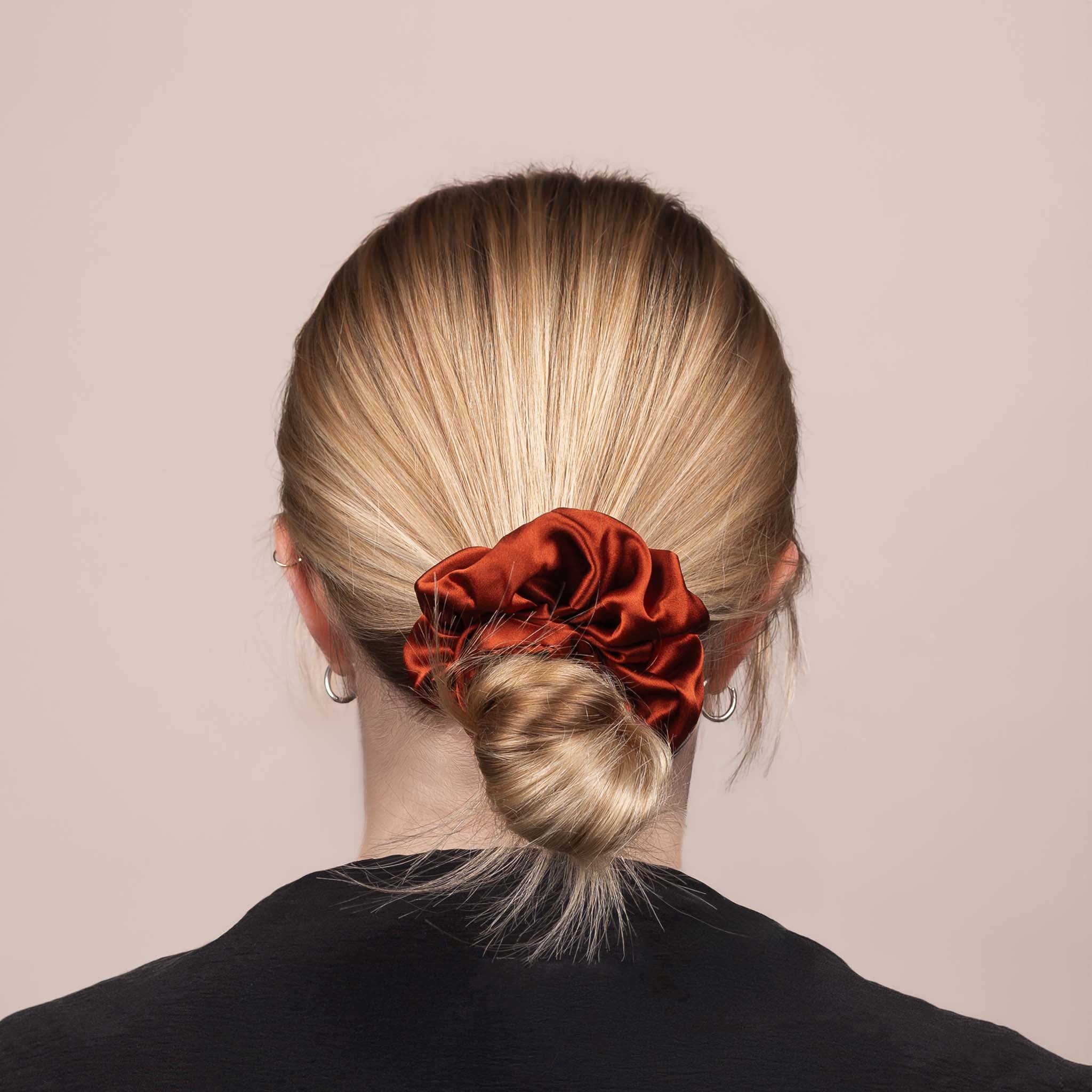 Back view of the Large Silk Scrunchie in Deep Terracotta securing hair in a low bun, showing its soft sheen and gentle drape.