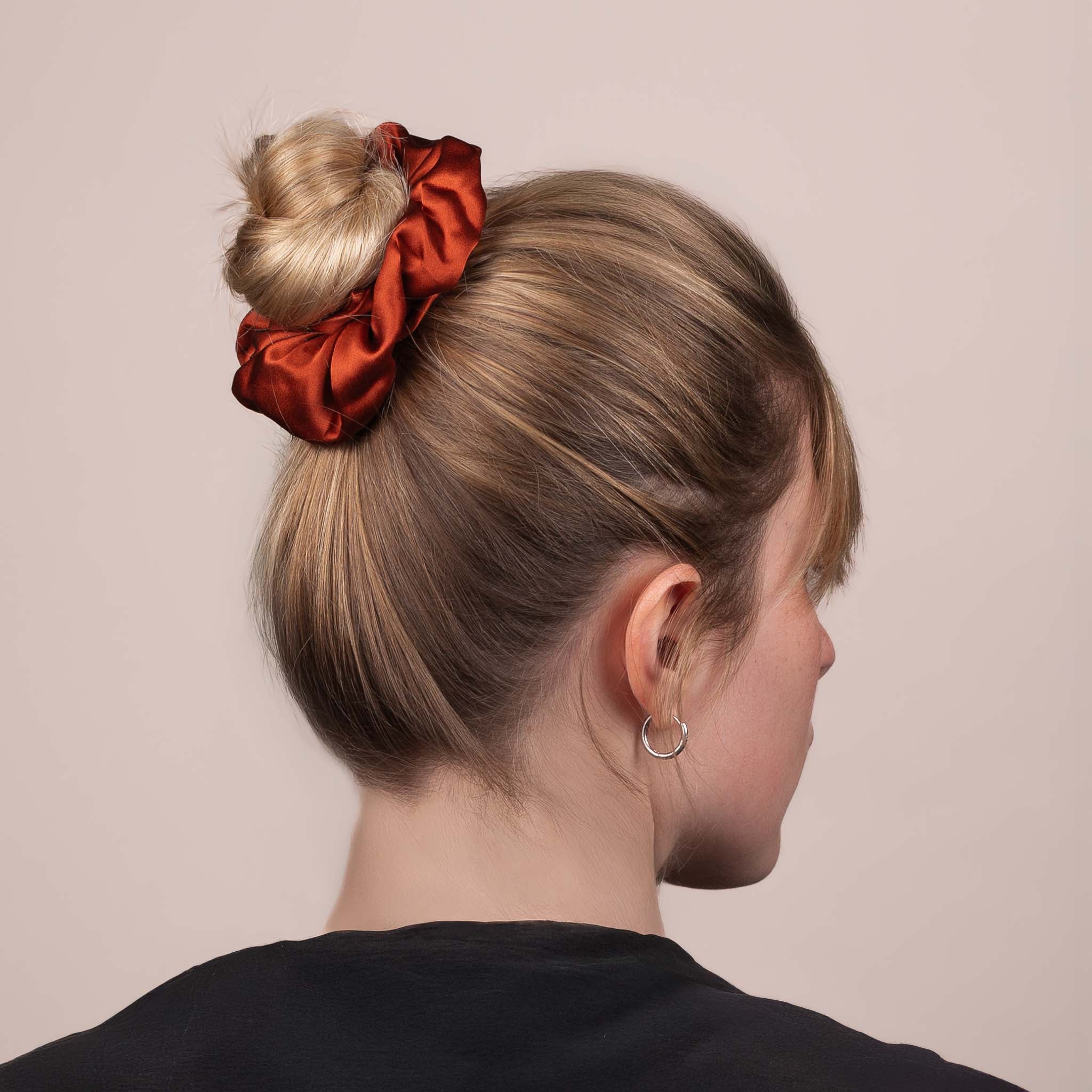 Side view of the Large Silk Scrunchie in Deep Terracotta securing hair in a high bun, showing its soft sheen and gentle drape.