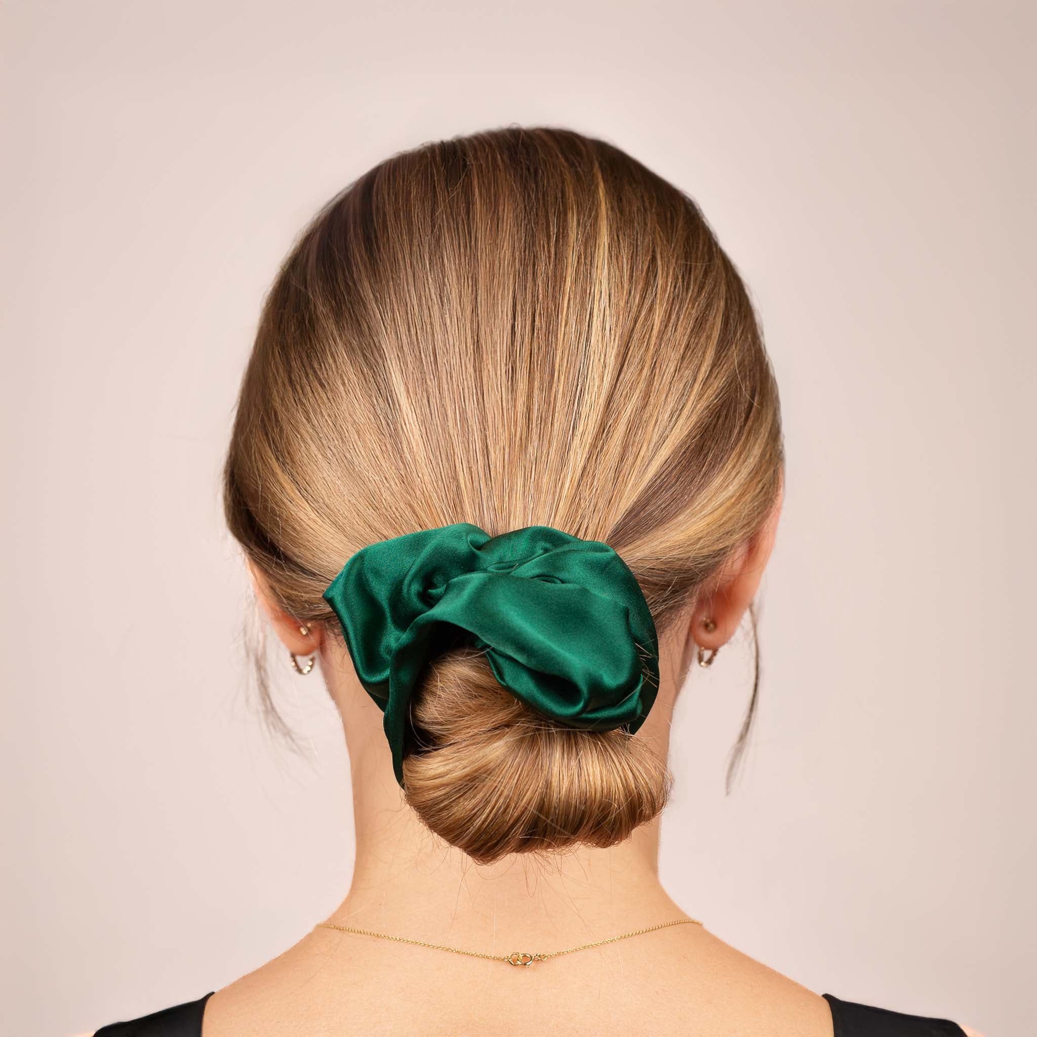 Back view of the Large Silk Scrunchie in Emerald Green securing hair in a low bun, showing its soft sheen and gentle drape.