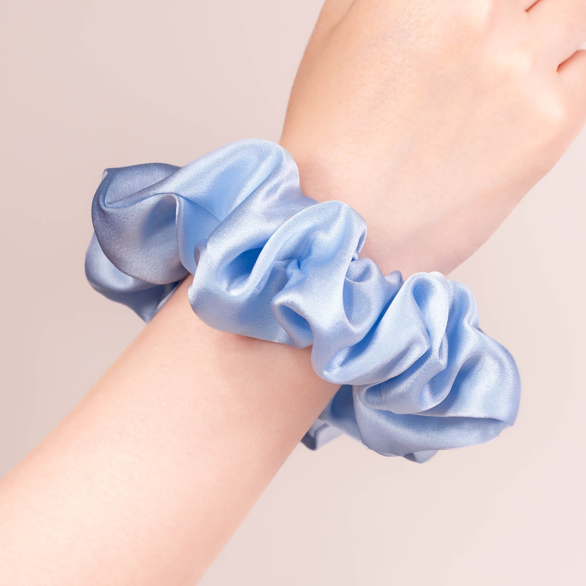 Large Silk Scrunchie in Icy Blue—a crisp light blue —worn on a wrist, showing a natural soft sheen and gentle drape.