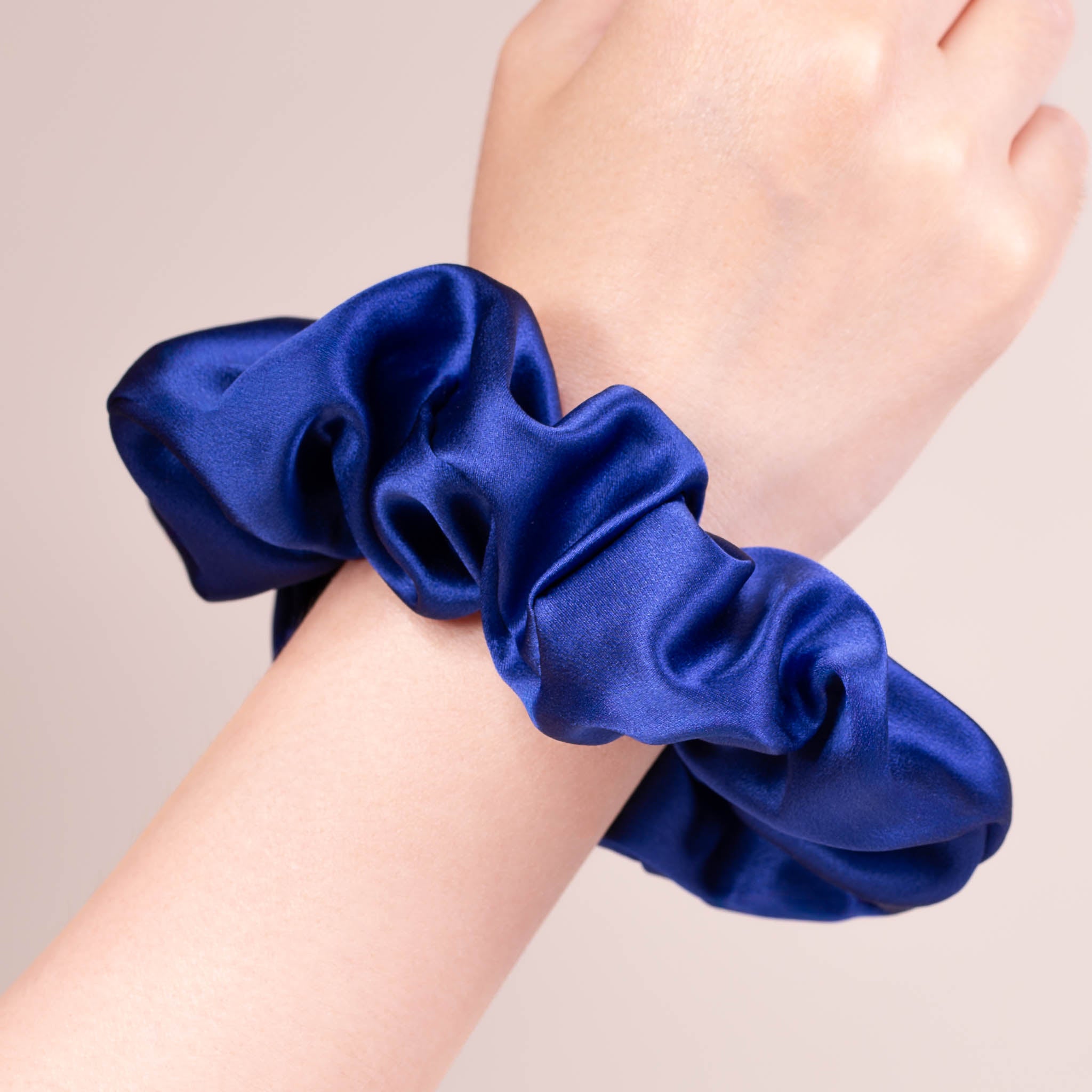 Large Silk Scrunchie in Navy Blue—a deep cool navy blue—worn on a wrist, showing a natural soft sheen and gentle drape.