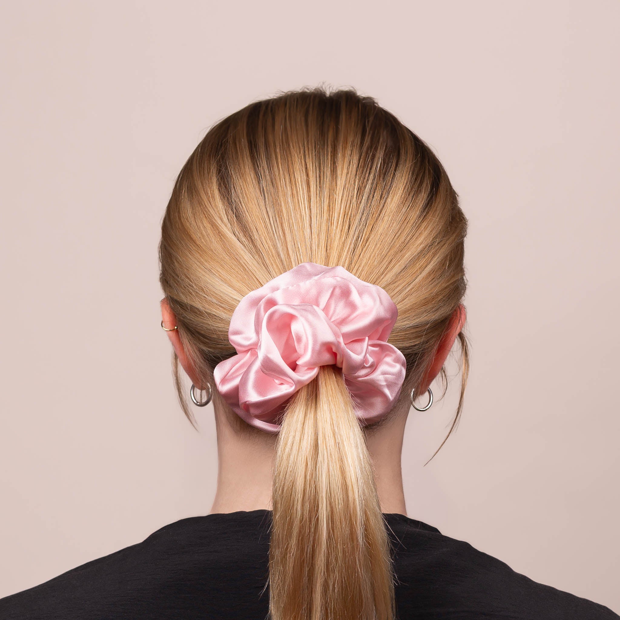 Back view of the Large Silk Scrunchie in Peony Pink, securing hair in a low ponytail, with a soft sheen and drape.
