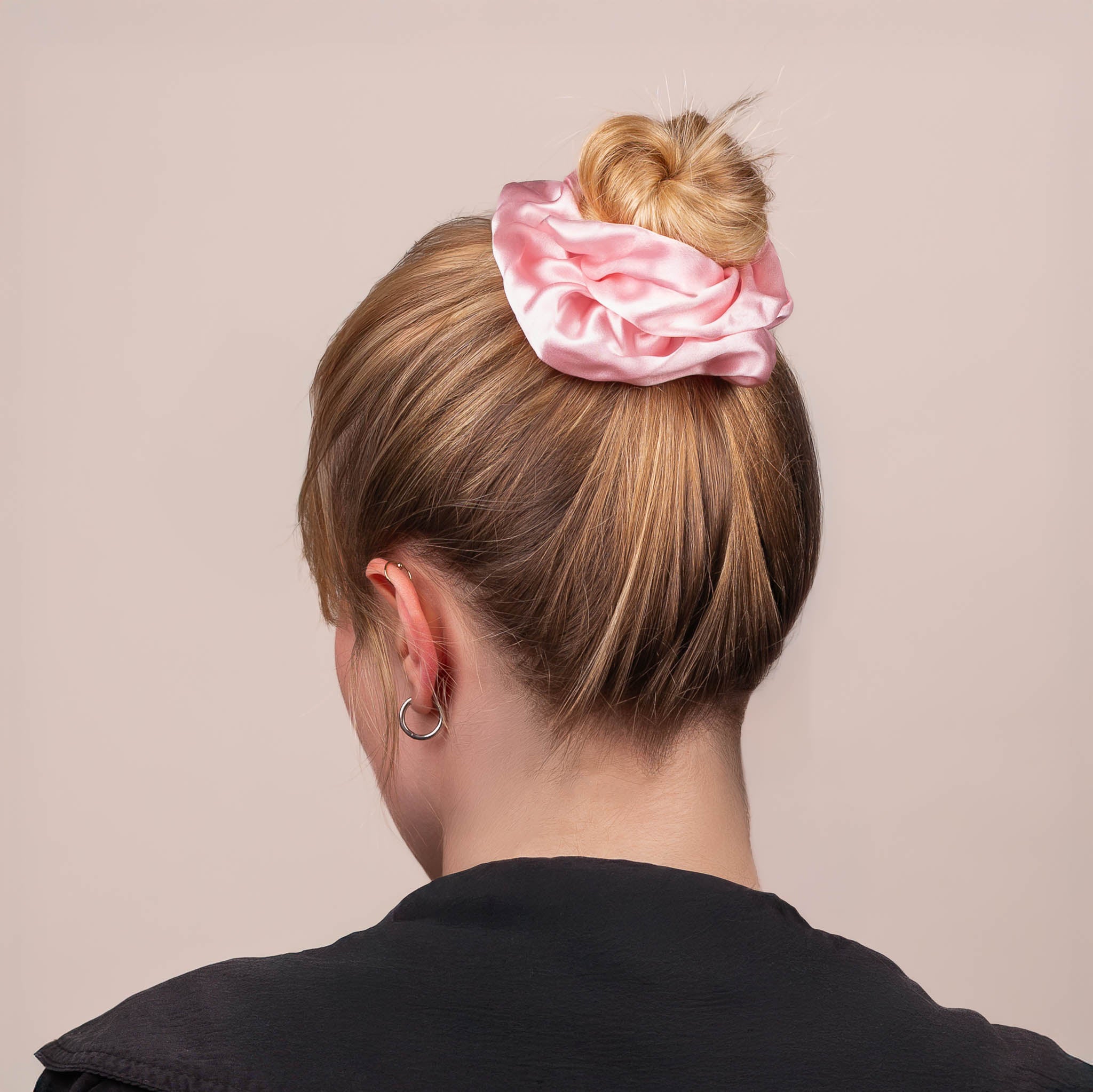 Back view of the Large Silk Scrunchie in Peony Pink securing hair in a high bun, showing its soft sheen and gentle drape.