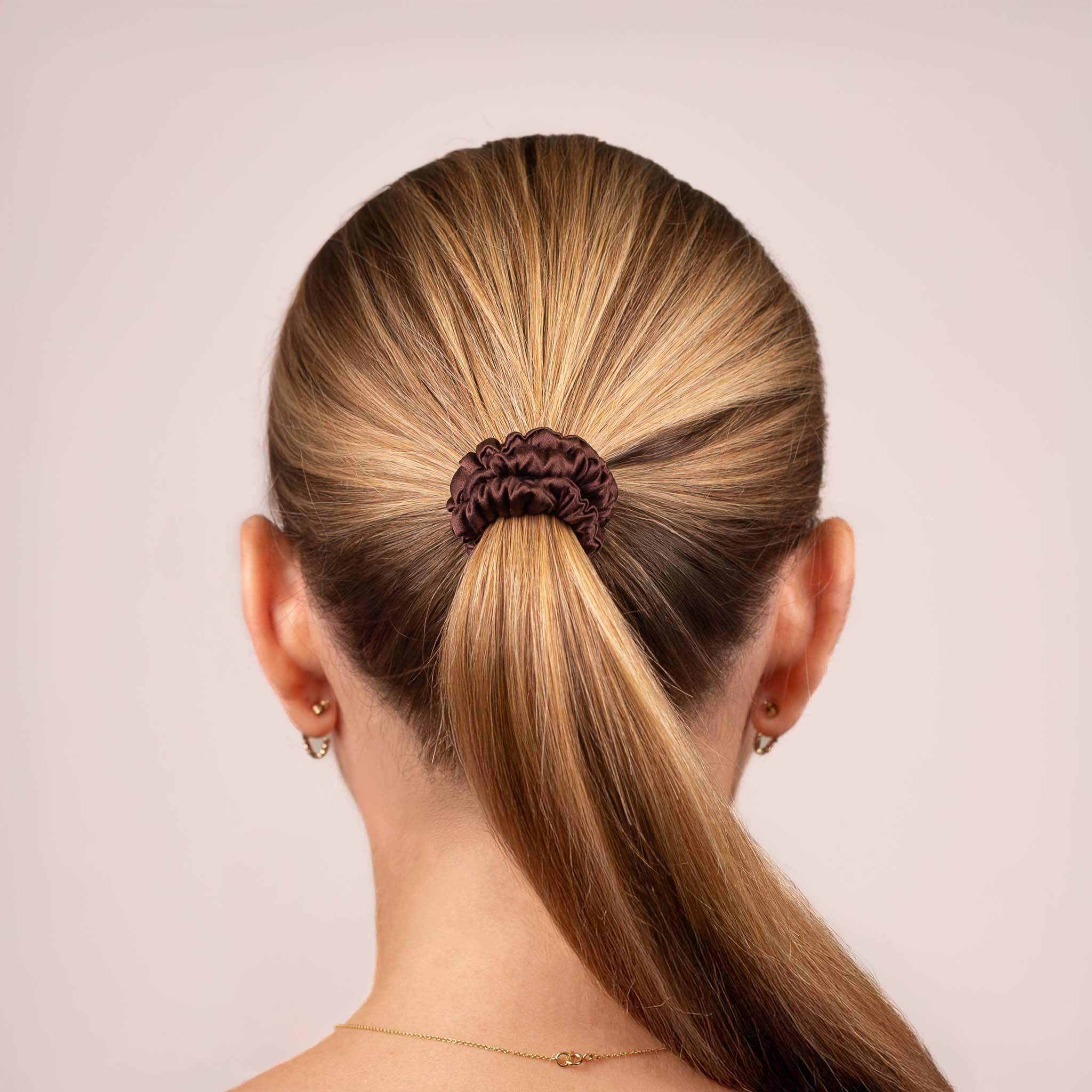 Skinny Silk Scrunchie in Dark Brown securing a high ponytail, shown from the back, highlighting its smooth texture and soft sheen.