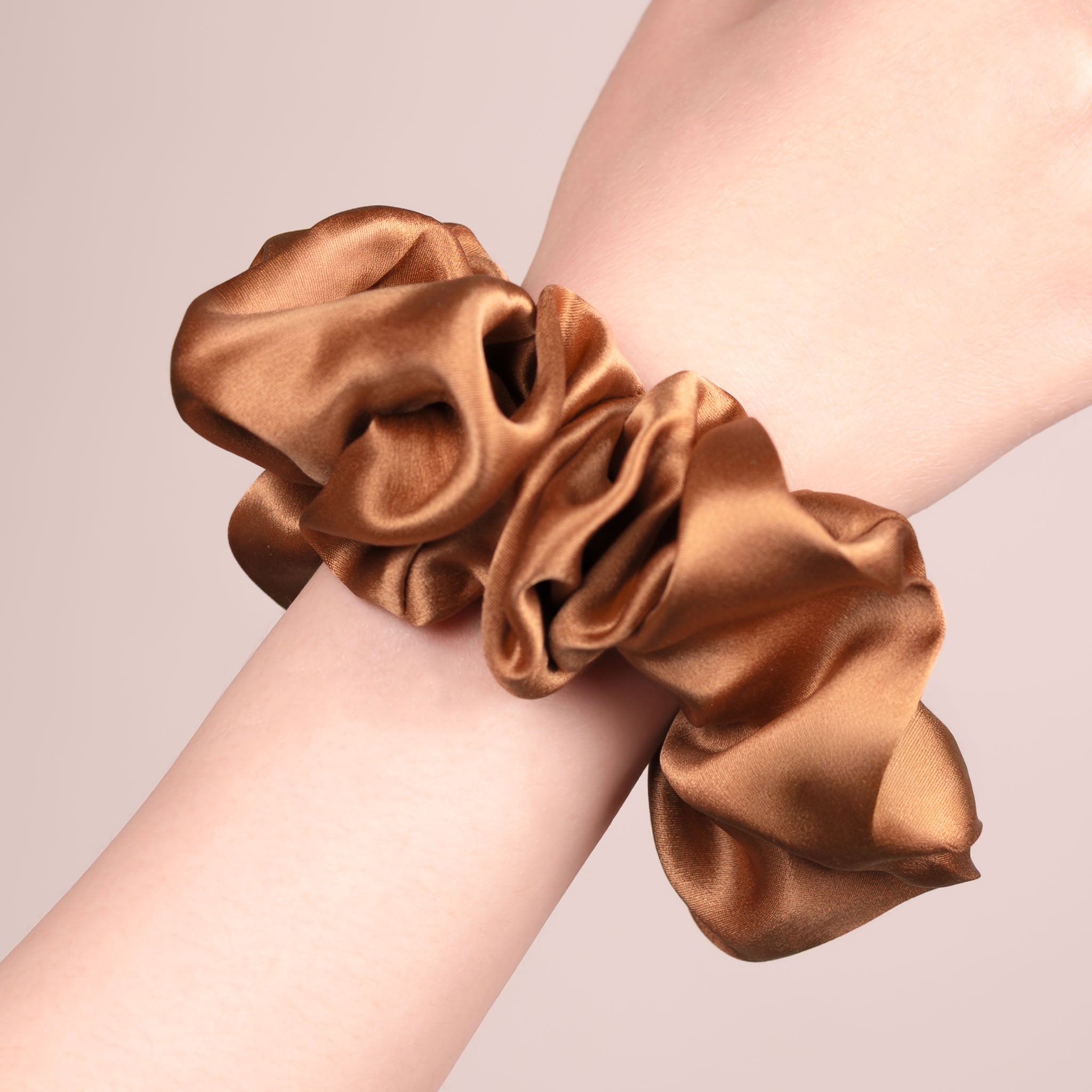 Large Silk Scrunchie in Caramel Brown—a warm light brown —worn on a wrist, showing a natural soft sheen and gentle drape.
