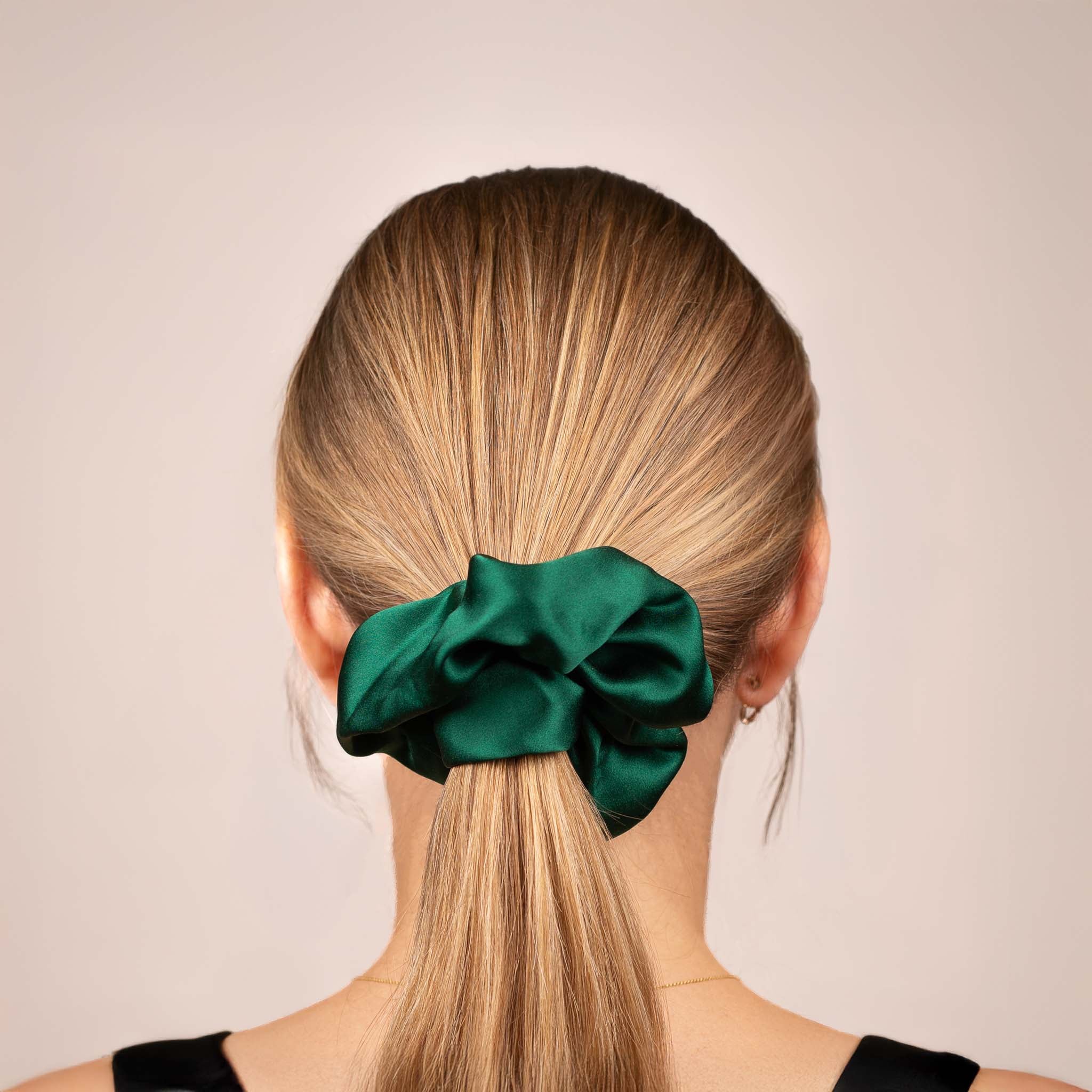 Back view of the Large Silk Scrunchie in Emerald Green, securing hair in a low ponytail, with a soft sheen and drape.