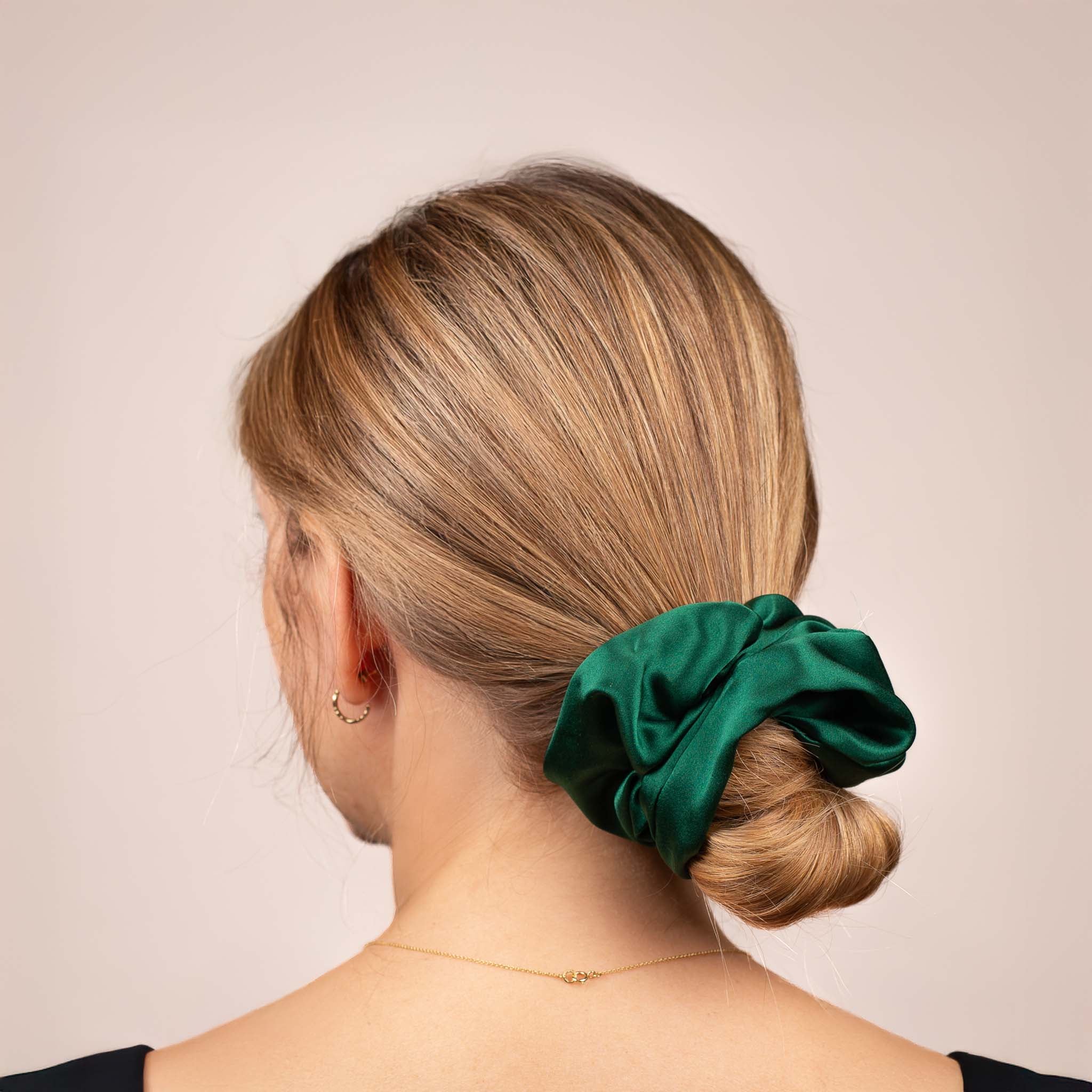 Side view of the Large Silk Scrunchie in Emerald Green securing hair in a low bun, showing its soft sheen and gentle drape.