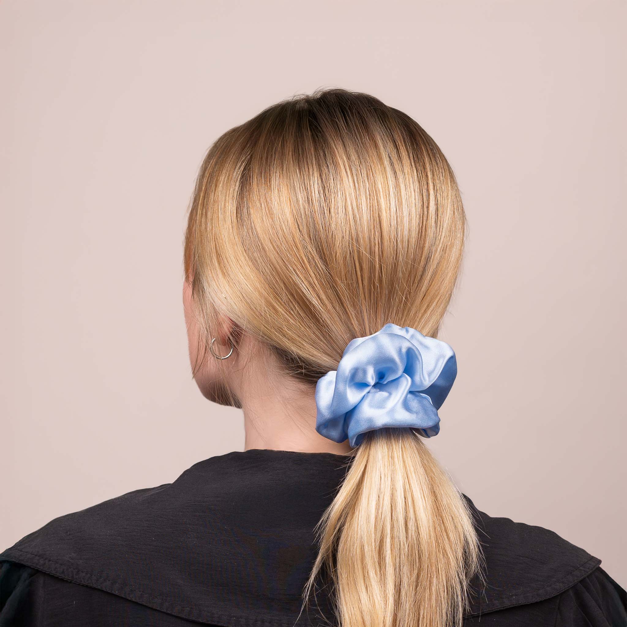 Side view of the Large Silk Scrunchie in Icy Blue securing hair in a low ponytail, with a soft sheen and drape.