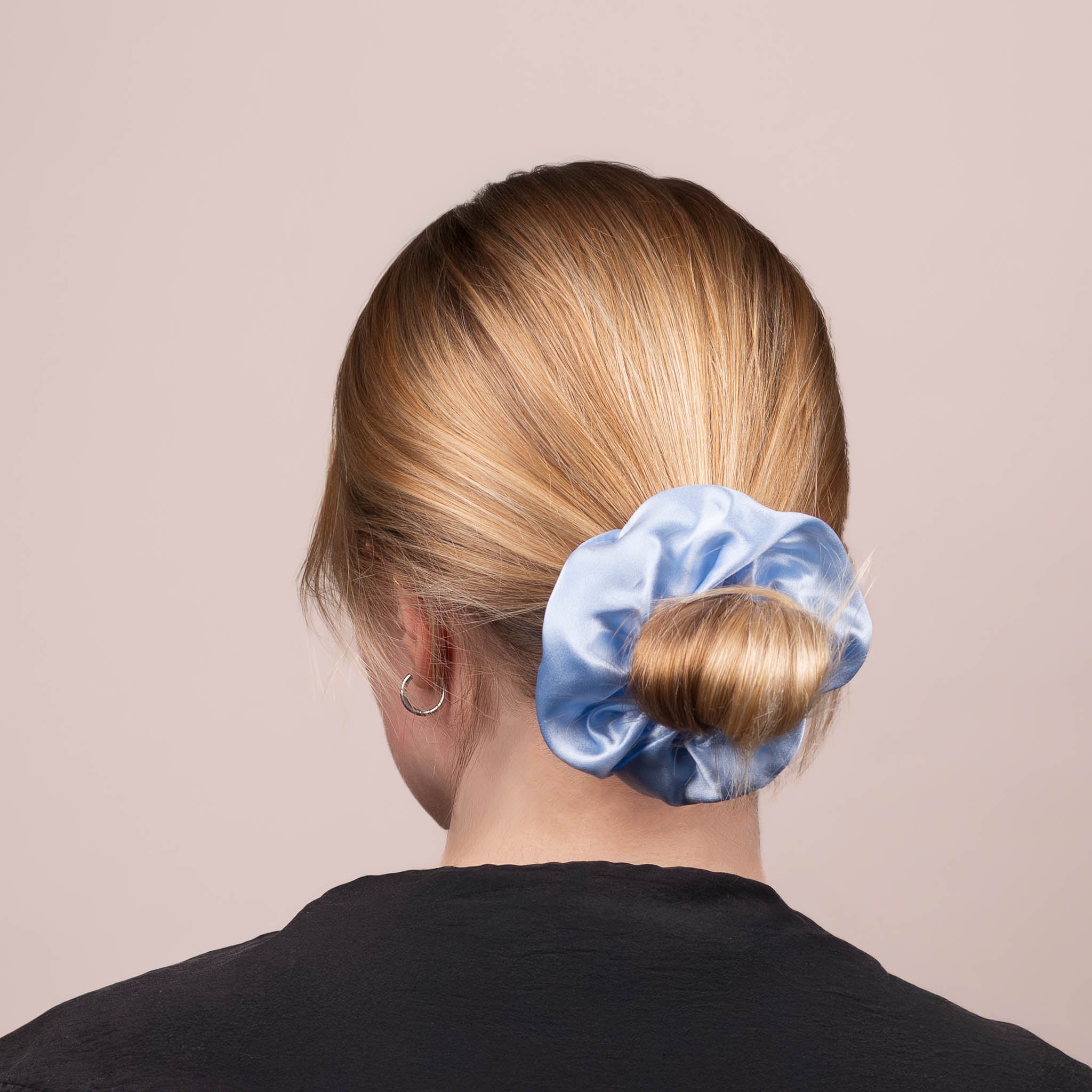 Back view of the Large Silk Scrunchie in Icy Blue securing hair in a low bun, showing its soft sheen and gentle drape.