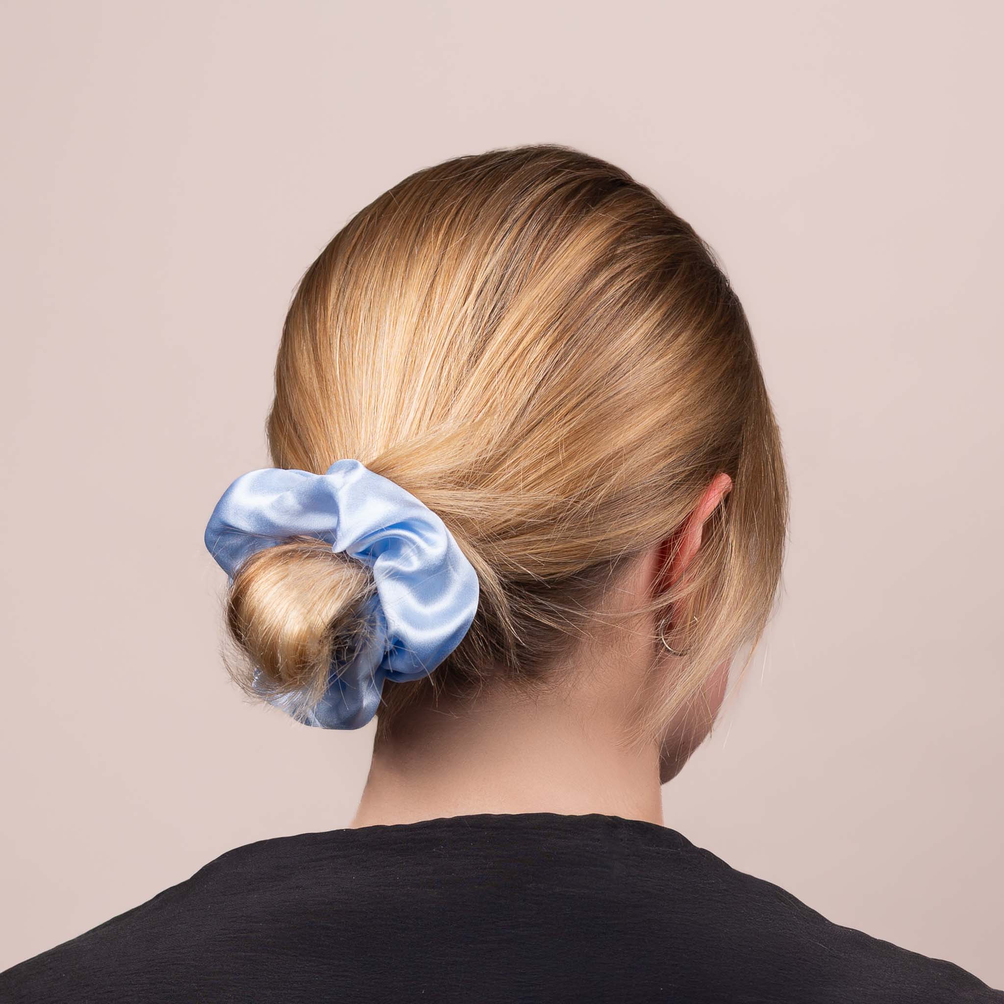 Side view of the Large Silk Scrunchie in Icy Blue securing hair in a low bun, showing its soft sheen and gentle drape.
