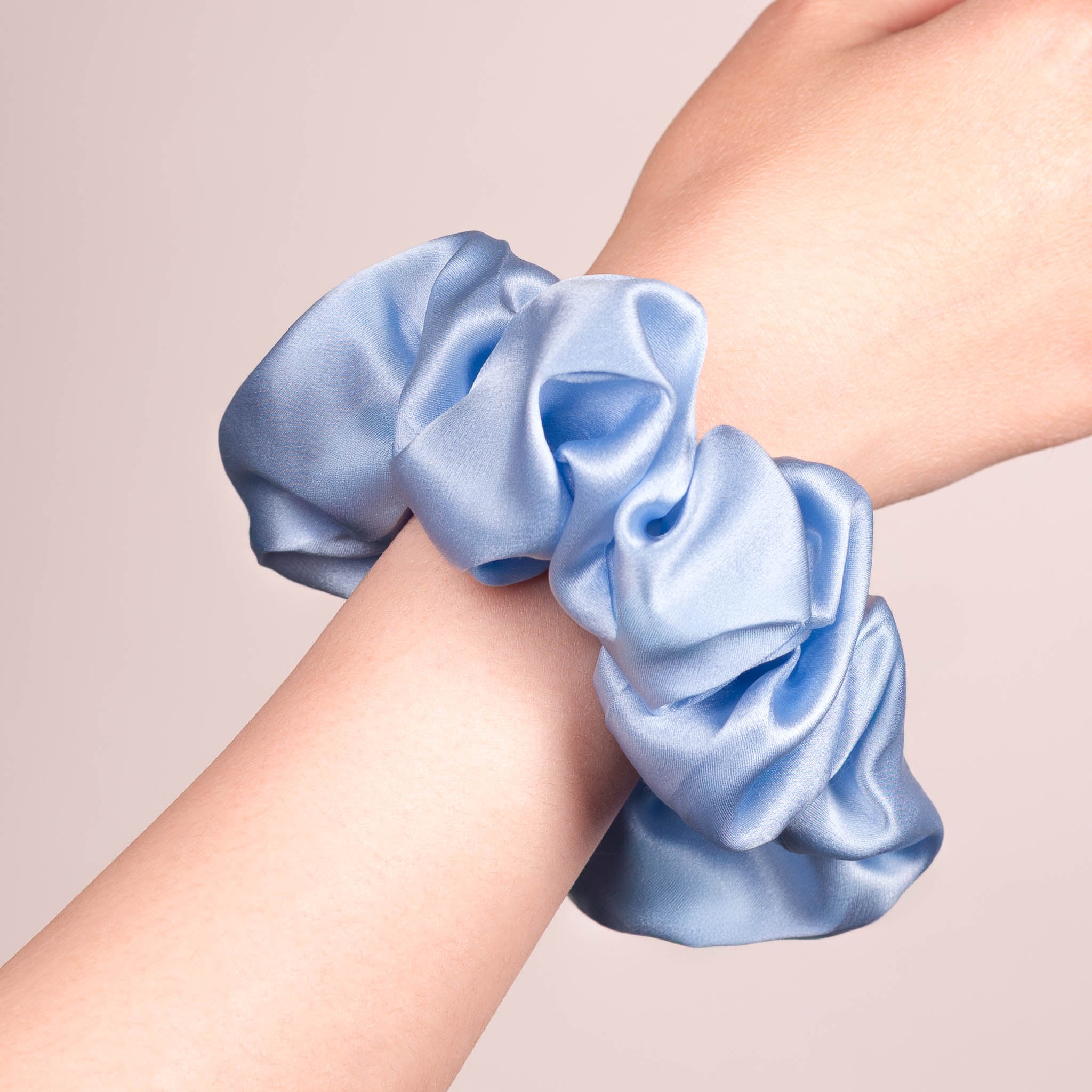 Large Silk Scrunchie in Icy Blue—a crisp light blue —worn on a wrist, showing a natural soft sheen and gentle drape.