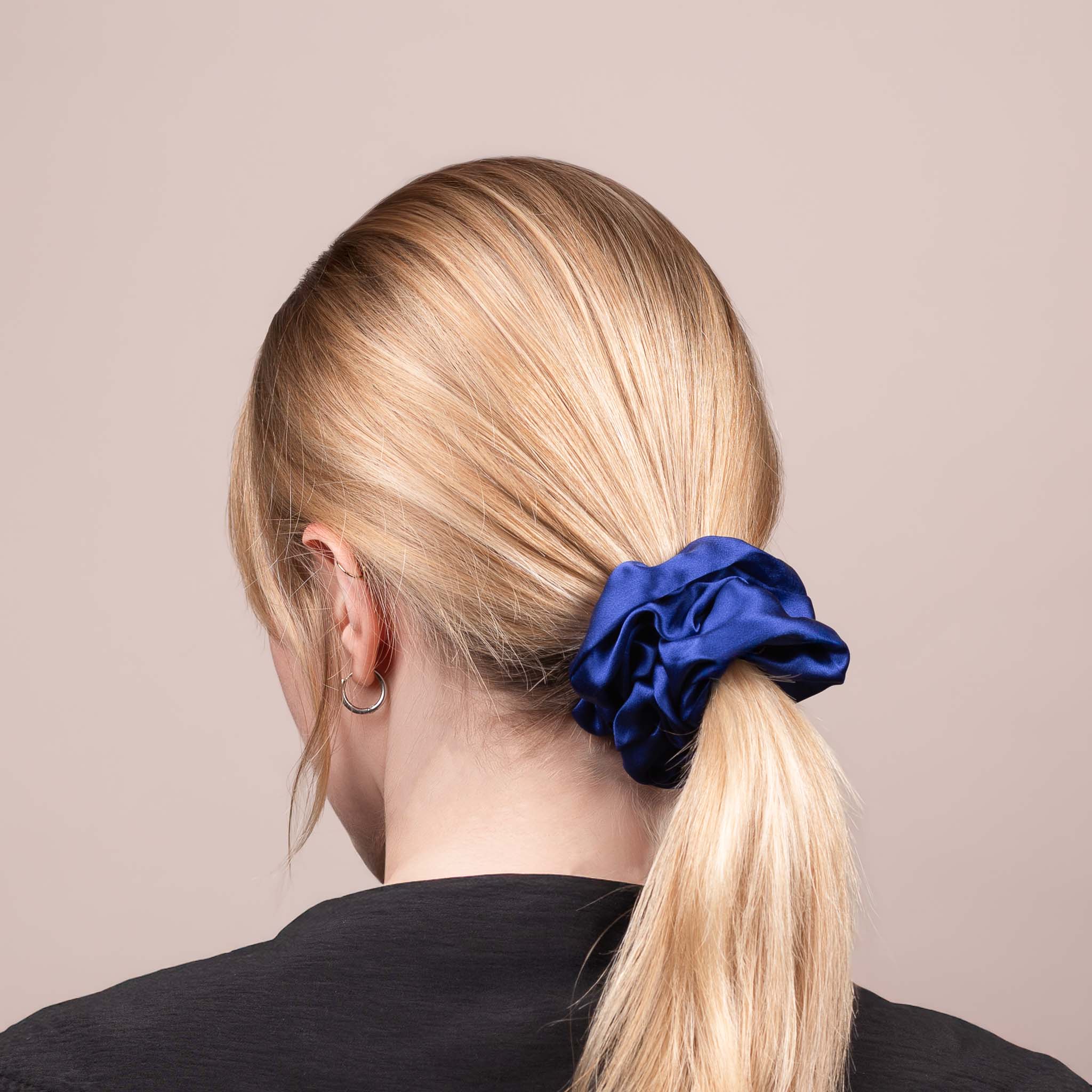 Side view of the Large Silk Scrunchie in Navy Blue securing hair in a low ponytail, with a soft sheen and drape.