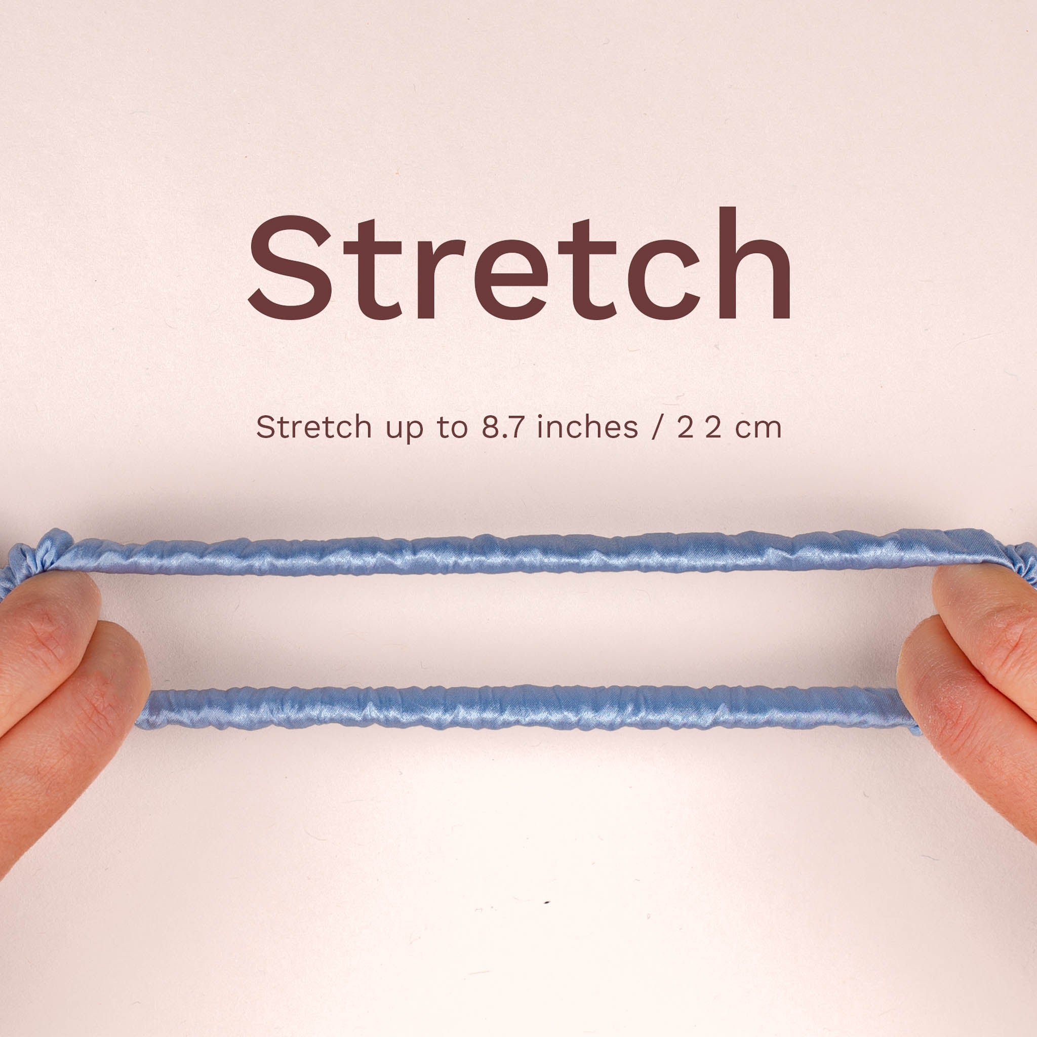 Skinny silk scrunchie shown stretched between hands, stretching up to 8.7 inches (22 cm).