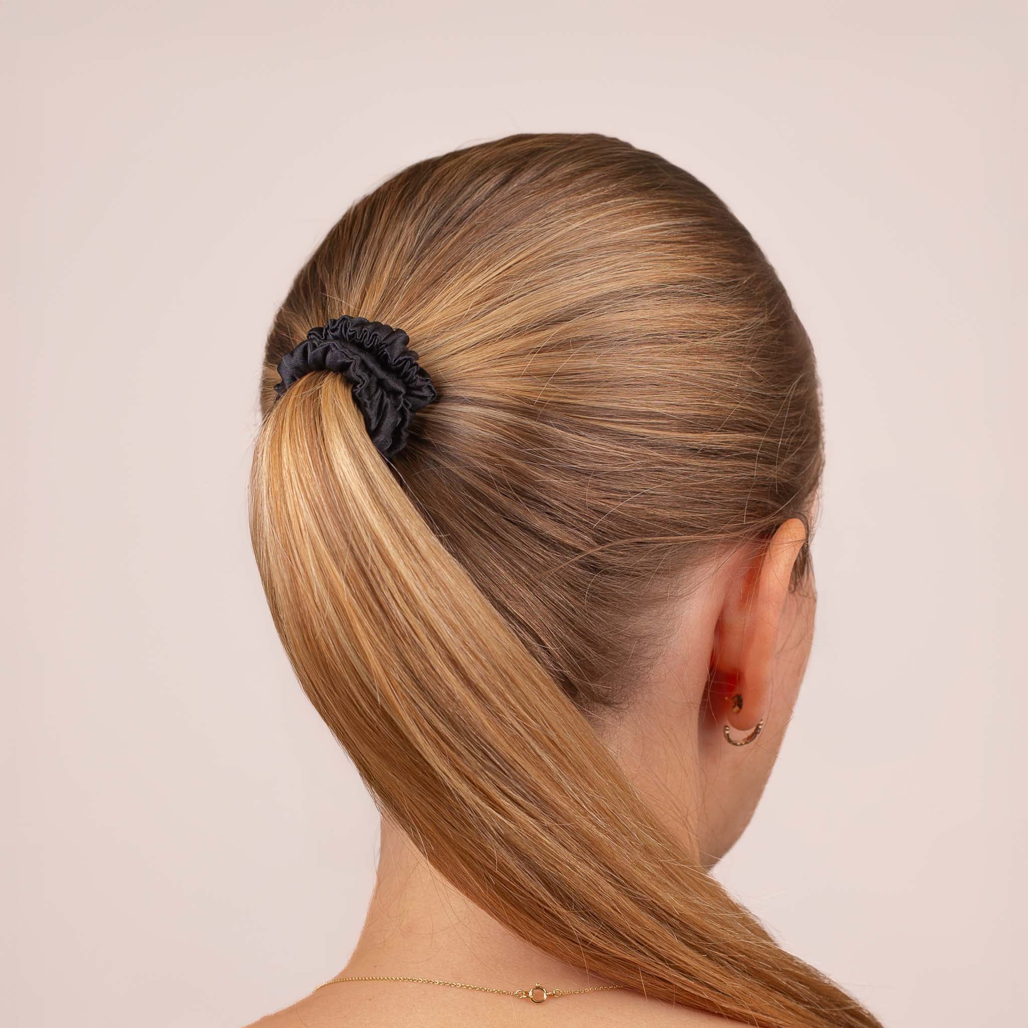 Skinny Silk Scrunchie in Black securing a high ponytail, shown from the back, highlighting its smooth texture and soft sheen.