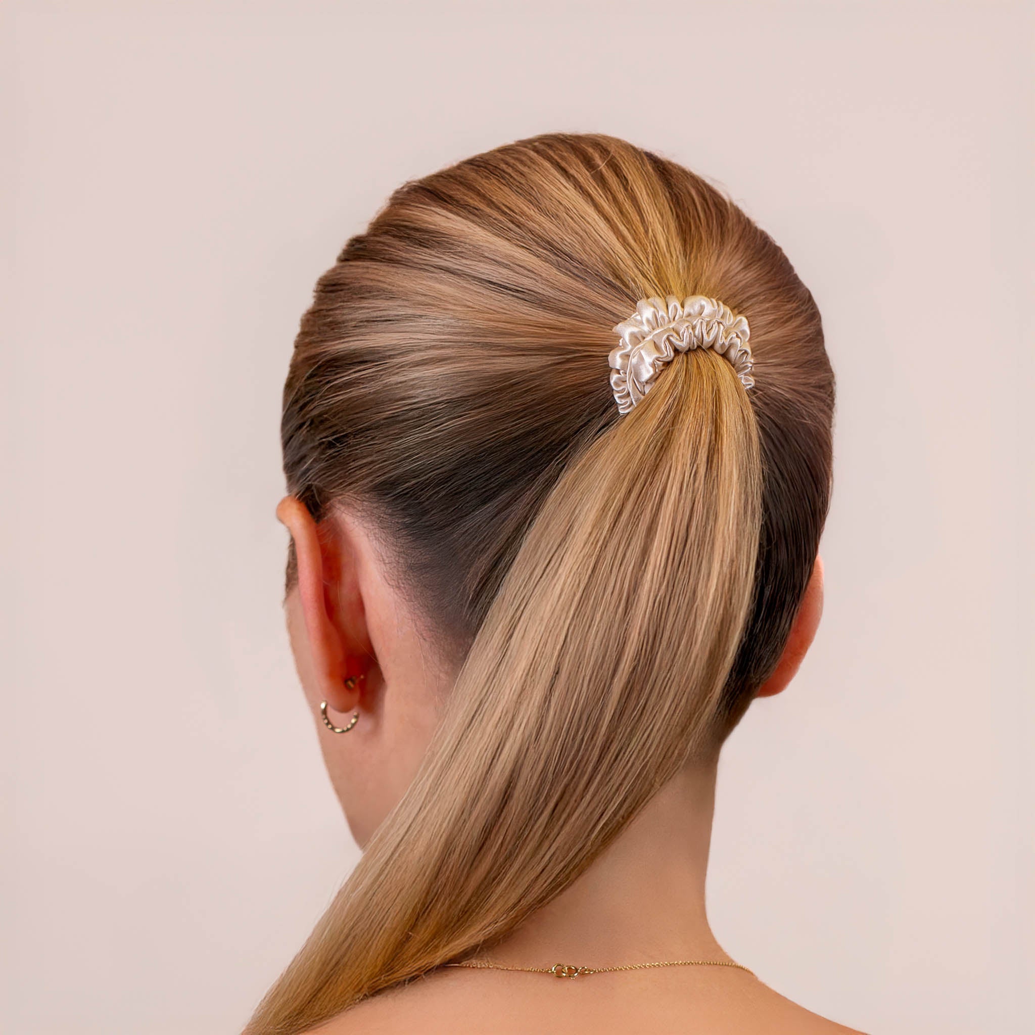 Skinny Silk Scrunchie in Champagne securing a high ponytail, shown from the back, highlighting its smooth texture and soft sheen.