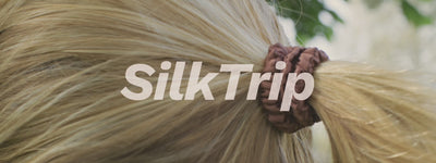 Woman running in the park with her hair securely tied in a ponytail using a Skinny Silk Scrunchie from SilkTrip.