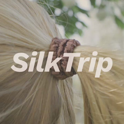 Woman running in the park with her hair securely tied in a ponytail using a Skinny Silk Scrunchie from SilkTrip.